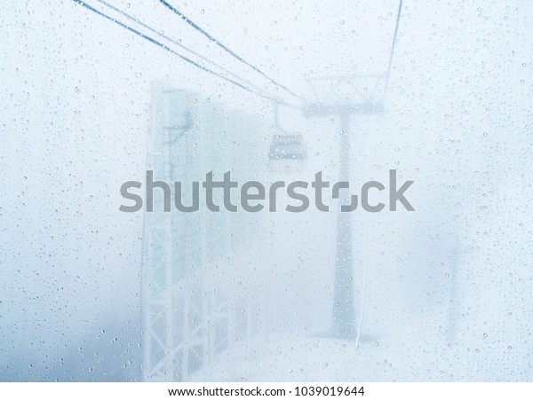 cable car transport electrical winter storm\
blizzard rain mountain white sky, snow background, ski cars pole\
equipment high engineering steel industrial nature heavy station\
travel mountains danger.