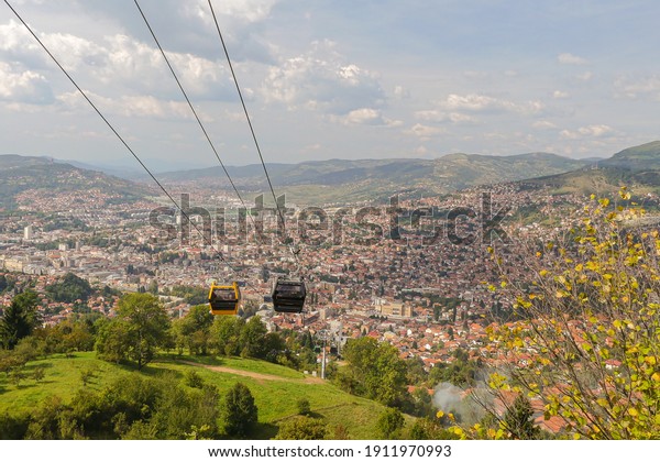 A cable\
car wire above the city of Sarajevo and the surrounding hills and\
mountains, Bosnia-Herzegovina during\
daylight