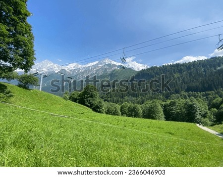 cable cars in the alps with mountain range background and alpine views of the valley bellow and above the tree line 