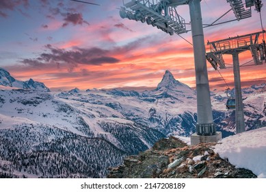 Cable cars moving by snowcapped matterhorn. Aerial tramcar against cloudy sky during sunset. Scenic view of mountain range during winter.