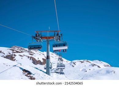 Cable cars moving over snowy mountain. Aerial tramcar against clear blue sky. Scenic view of white landscape in alps during winter.