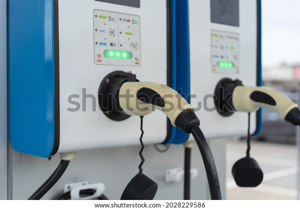 Cable\
from EV car charger or electric vehicle station. Cable connected at\
gas station, power supply battery charging an alternative eco\
environment future technology energy\
innovation