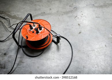 Cable reel Orange color Be plugged with Black Cable Wire Placed on the floor.