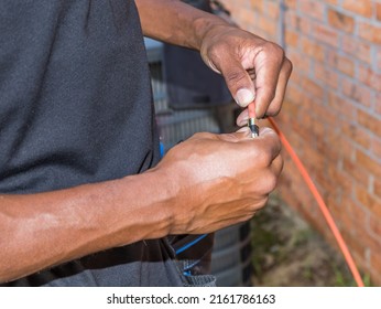 Cable Repair Man Servicing A Coaxial Internet And Video Cable Junction On A Residential Home Façade.