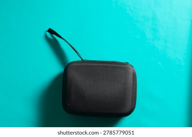Cable storage pouch bag and electronic accessories in black with a blue background,