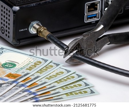 Cable TV cord being cut with cash money. Cord cutting, wireless, streaming television concept.
