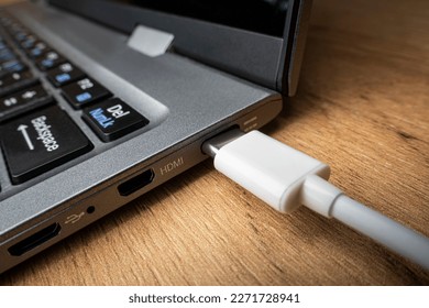 Cable USB adapter under the Type-C connector is installed in the laptop against the background of a wooden table