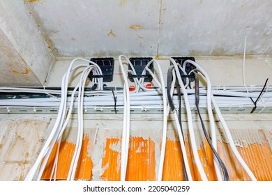 Cables Are Hanging From Ceiling Of Building Under Construction, Work In Progress. Placement Of Electrical Wires And Cables.