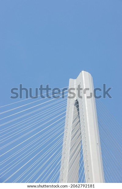 cable-stayed bridge close-up, main tower and cable\
against a blue sky