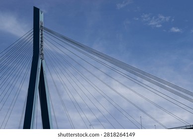 Cable-stayed bridge features blue support towers and suspension cables under a clear sky, highlighting modern architectural design and engineering techniques
