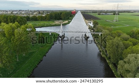 Cable-stayed bridge on one of the canals in the vicinity of Almere, Netherlands. This picturesque bridge is located on the outskirts of a residential area and a farm.