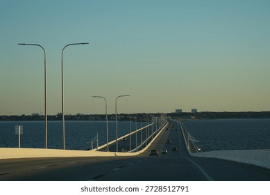 Cable-stayed bridge viewed from approaching vehicle under clear sky.