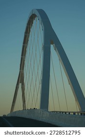 Cable-stayed bridge viewed from approaching vehicle under clear sky.