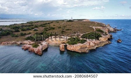 Cabo Rojo Lighthouse in the background, with a small rock bridge seen above the arc.