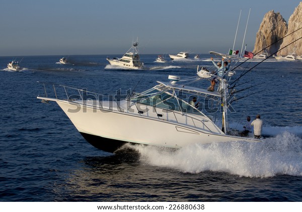 Cabo San Lucas, Mexico - Oct 24, 2014: Sport fishing\
boats taking off at the start of a fishing tournament in Cabo San\
Lucas with Land\'s End in the background in Cabo San Lucas, Mexico -\
Oct 24, 2014 