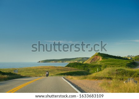 Cabot trail coastline in Cape Breton Island, Nova Scotia during the summer season. A motorcycle is visible along the road.