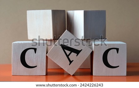 CAC - acronym on large wooden cubes on light brown background. Business concept