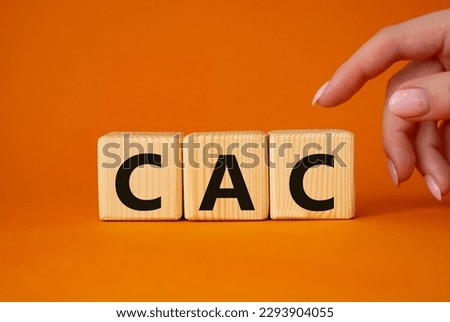 CAC - Customer Acquisition Cost symbol. Wooden cubes with word CAC. Beautiful orange background. Businessman hand. Business and Customer Acquisition Cost concept. Copy space.