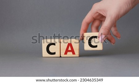 CAC - Customer Acquisition Cost symbol. Wooden cubes with word CAC. Beautiful grey background. Businessman hand. Business and Customer Acquisition Cost concept. Copy space.