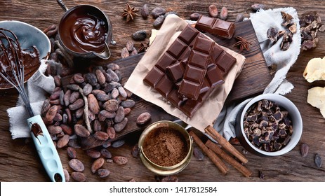 Cacao beans, powder, cacao butter,  chocolate bar and chocolate sauce on wooden background - Shutterstock ID 1417812584