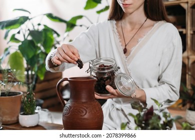 Cacao Ceremony In Atmospheric Space With Green Plants And Candles. Woman Making Ritual Healthy Drink From Cocoa Beans. Person Putting Sweet Dried Fruits Date To Hot Fresh Chocolate Drink