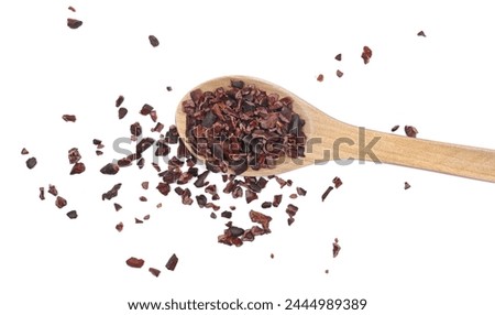 Cacao nibs, crushed and peeled cocoa in wooden spoon, isolated on white, top view