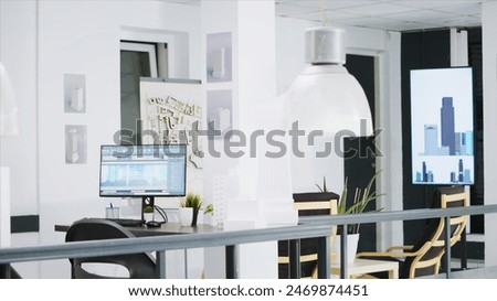 Cad modeling system running on PC at a empty workstation, urbanistic designs and layouts on table. Innovative architectural creative business desktops equipped with manufacturing tools.