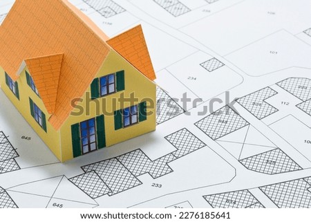 Cadastral map with buildings, building plot and free land parcel for house construction - building activity and permit concept with home model