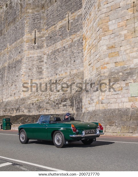 CAERNARFON, WALES\
- 29 SEPTEMBER 2013: Vintage classic MG car taking part in the\
Walled Towns Trail Car Run 2013 passes the walls of Caernarfon\
Castle en route to its next\
destination
