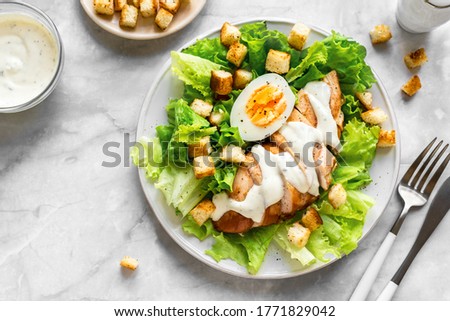 Caesar salad with chicken breast on marble background, top view, close up. Fresh chicken salad for healthy lunch.