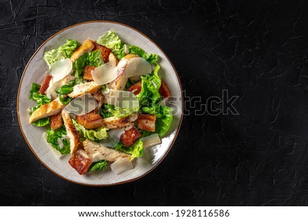 Caesar salad with chicken, shot from above with copy space on a black background