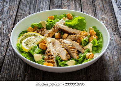 Caesar salad - fried chicken breast and vegetables on wooden table 