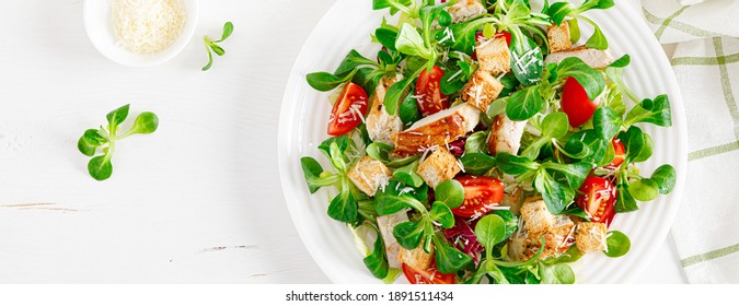 Caesar-Salat mit gegrilltem Hühnerfleisch, frischer Tomate, Croutons, Lammsalat und Parmesan-Käse. Gesundes Mittagessen. Draufsicht. Banner
