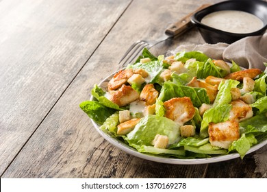 Caesar salad with lettuce,chicken and croutons on wooden table. Copyspace