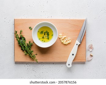 Caesar Salad. Step By Step Cooking Process. Step 3. Olive Oil Mix With Green Thyme Leaves And Chopped Garlic Clove. Grey Concrete Background. Top View. Preparation Of Healthy Lunch Or Dinner. 