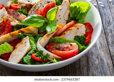 Caesar style salad - grilled chicken breast and fresh vegetables on wooden table - Powered by Shutterstock