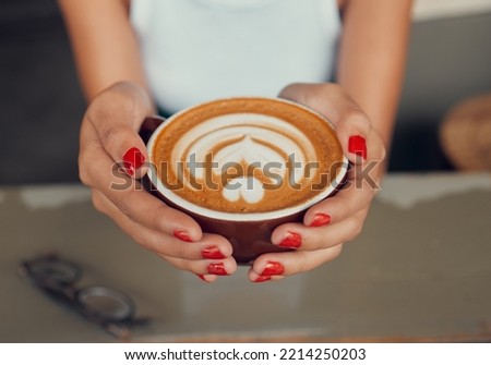 Cafe, art and coffee woman hands holding caffeine drink cup for leisure break with top view. Barista, espresso and design of cappuccino beverage of girl customer at restaurant table close up.