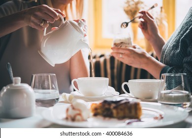 Cafe or bar table with desserts and tea. Two people talking on background. Toned picture - Shutterstock ID 400084636