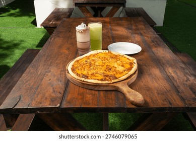 cafe dining table featuring cheese sausage pizza, breakfast rice plate with omelet and sausages, toast with melted cheese, and assorted drinks in a cozy restaurant setting.
