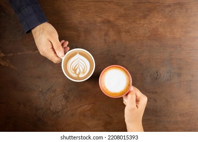 Cafe latte, top view photo of couple drinking cafe latte. Wooden cafe table, copy space  area. Hot fresh coffee and cappuccino. Woman, male hand holding mug. Cafe menu concept idea background. - Powered by Shutterstock