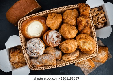 Cafe menu, breakfast basket. Fresh pastries: croissants, rolls, puffs and bun with sour cream in basket with chicken and pasta in paper boxes. Top view.