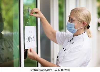 Cafe Opening After Lockdown. Open Sign On Front Door Of Restaurant Or Grocery Store. Waiter In Apron Greeting Customer. Welcome Message On Bakery Entrance. Back To Work After Quarantine.