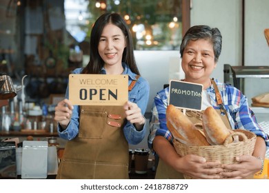 Cafe owner Retired elderly mother holding basket bread beautiful Asian daughter small businessman employee barita waiter holding welcome sign opening up both smiling each other promote family store - Powered by Shutterstock