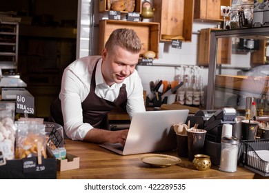 Cafe Owner Working On Laptop Behind The Counter