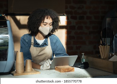 Cafe Restaurant, Good Service, Small Business Owner, Food And Drink. Millennial African American Lady In Apron, Gloves And Protective Mask Works With Tablet And Takes Online Order At Bar In Cafeteria