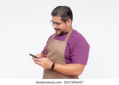El dueño de una cafetería o el gerente usando su celular mientras sonríe. Aplicación de entrega de comida por teléfono o concepto de detalles de contacto. Foto de cuerpo completo, aislada de fondo blanco.