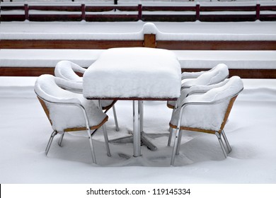 Cafe With Snow. Winter Landscaper. Garden Furniture Melting After A Snowstorm.