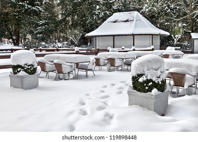 Cafe With Snow. Winter Landscaper. Garden Furniture Melting After A Snowstorm.