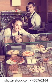Cafe staff offering fancy and sponge cakes for sale