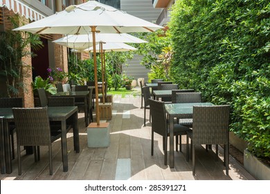 Cafe Tables And Chairs Outside With Big White Umbrella And Plant